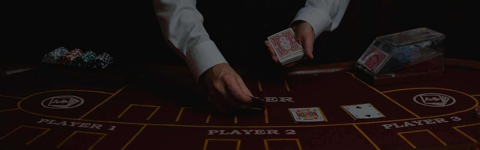 カジノで男性のディーラーがテーブルにトランプを並べている様子